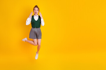 Young red-haired student expressing excitement in stylish uniform posing joyfully against a vibrant...