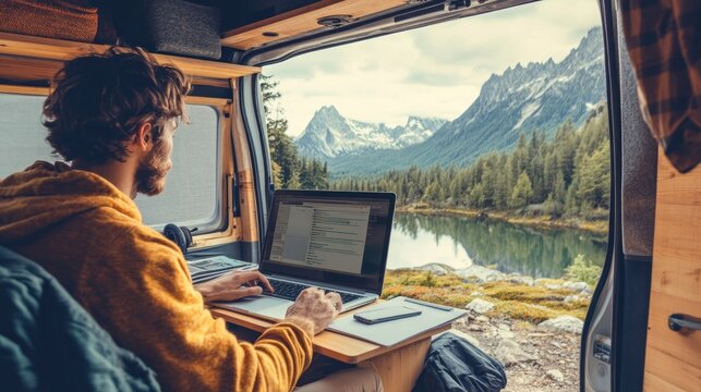 Man working on laptop in van by a lake