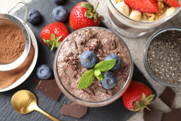Delicious chocolate pudding with chia seeds, strawberries and blueberries in glass on light grey table, flat lay