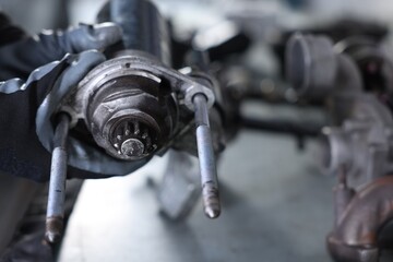 Auto parts. Professional mechanic with starter motor at table indoors, closeup. Space for text