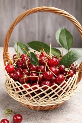 Wet ripe cherries in basket on light table, closeup