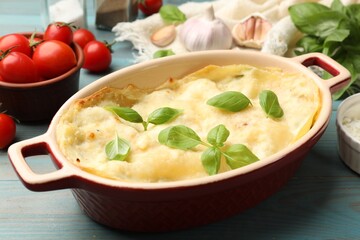 Tasty vegetarian lasagna and ingredients on light blue wooden table, closeup