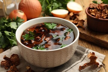 Tasty soup with mushrooms and parsley in bowl on wooden table, closeup