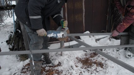 A group of construction workers are cutting metal frames together in a snowy and rural environment today