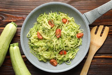 Tasty zucchini noodles with tomatoes and thyme on wooden table, flat lay