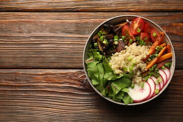 Healthy vegetarian food. Delicious Buddha bowl with quinoa, mushrooms and vegetables on wooden table, top view. Space for text