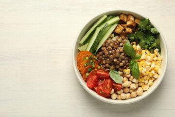 Healthy vegetarian food. Delicious Buddha bowl with lentils, tofu, chickpeas and vegetables on light wooden table, top view. Space for text
