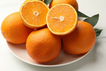 Whole and cut oranges on white table, closeup