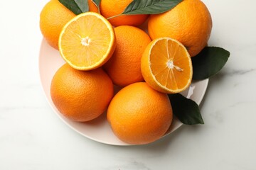 Fresh oranges and leaves on white table, top view
