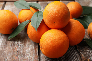 Fresh oranges and leaves on wooden table, closeup
