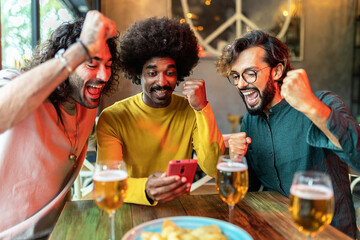 Three excited multiracial friends celebrating victory and winning online bet on match using betting...