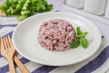 Cooked riceberry on white plate and white blackground with spoon and fork , riceberry it is a very useful rice