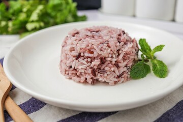 Cooked riceberry on white plate and white blackground with spoon and fork , riceberry it is a very useful rice
