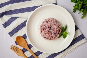 Cooked riceberry on white plate and white blackground with spoon and fork , riceberry it is a very useful rice