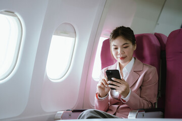 A woman in a pink blazer sits by the airplane window with eyes closed, relaxing peacefully during...