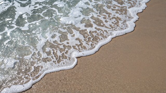 Soft white foam patterns forming on shallow waves near the shore