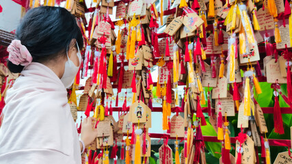 A little girl hangs a wooden sign bearing a wish on a bright red wish wall, adorned with wooden...