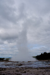 Erupting strokkur geyser in the golden circle of iceland on a cloudy day