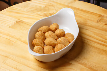 Typical Brazilian snack. Coxinha in a white bowl on a wooden table.