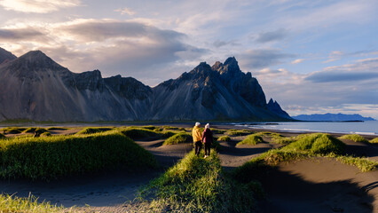 Couple exploring the stunning landscapes of Vestrahorn mountain in Iceland during sunset