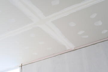 Interior building renovation progress showing new gypsum board ceiling with smooth edges ready for...