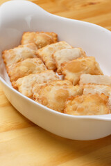 Delicious portion of fried pastries served in a white ceramic bowl on a wooden table.