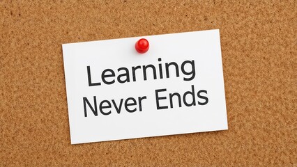 White paper pinned to cork board displaying 'Learning Never Ends'. Business inspiration