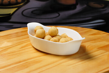 Delicious portion of fried cheese ball served in a white ceramic bowl on a wooden table.