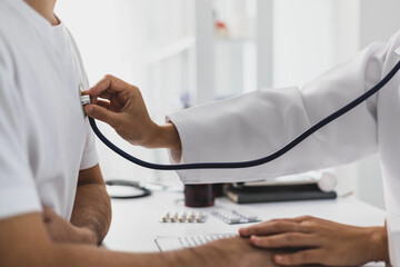 Female doctor examining patient with stethoscope in hospital room. Asian female doctor using...