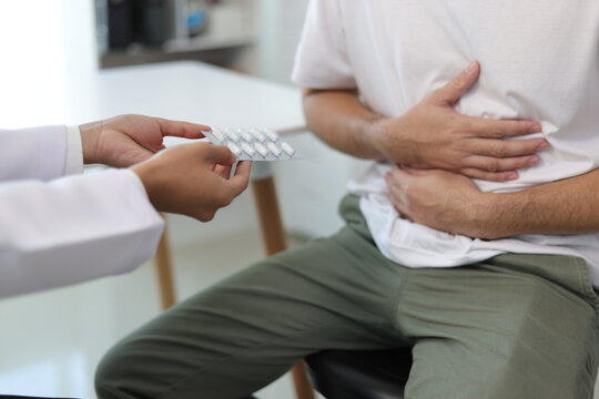 Man with abdominal pain, bloating, diarrhea goes to the doctor at medical clinic. Female doctor is diagnosing a patient abdominal pain in the examination room at the hospital.