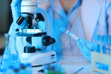 Medical scientist analyzing test tube with blue liquid in laboratory.