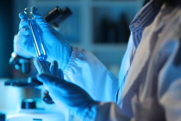 Medical scientist analyzing test tube with blue liquid in laboratory.