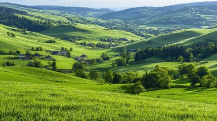 Fototapeta premium Rolling green hills with scattered houses and dense forests under a blue sky, showcasing serene rural countryside landscape.