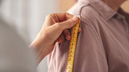 Tailor taking measurements on woman in atelier