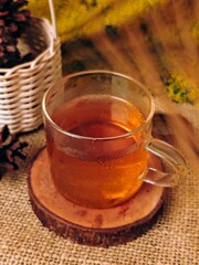 Steaming Tea in Clear Glass on Rustic Wood Coaster Pinecones.