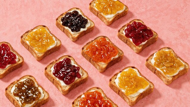 An array of toasts with diverse jam flavors displayed on pink
