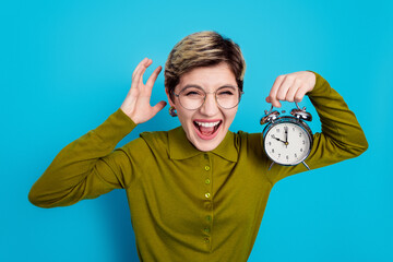 Young businesswoman holding retro alarm clock, promoting time management in a casual khaki shirt...