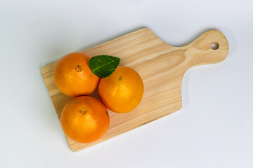 Three Bright Oranges on a Natural Wood Surface