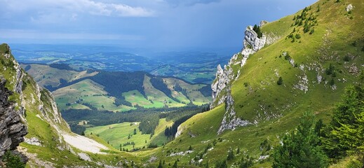 Mountain landscape with green meadows and view of the flatland behind the mountain saddle in the...