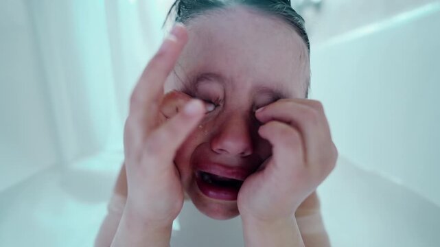 Boy crying in bathtub with hands over eyes, capturing intense emotion and raw moment of childhood distress, ideal for themes related to emotions, parenting, and mental health in stock photos
