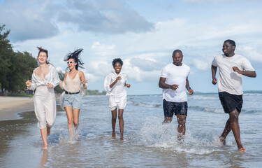group of multiracial friends enjoy running together on the beach in the evening