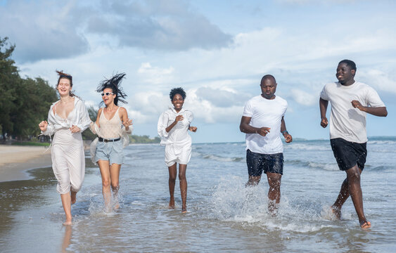 group of multiracial friends enjoy running together on the beach in the evening