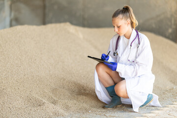Young woman vet with tablet checks purity and absence of impurities in granulated feed. Control...