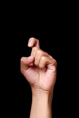 Hand gesture against black background.
