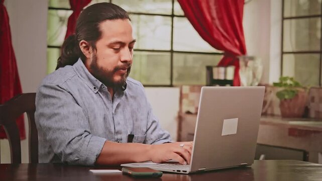 Latino man works on his laptop from home. Mayan Latino man uses technology to work from home.
