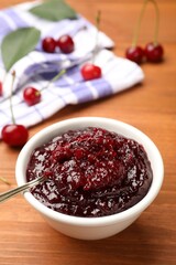 Tasty cherry jam and fresh fruits on wooden table, closeup