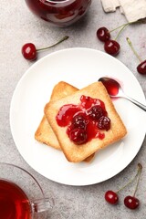 Toasts with tasty cherry jam, tea and fresh fruits on grey table, flat lay