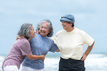 Happy senior women enjoying a playful walk on the beach, laughing and holding hands