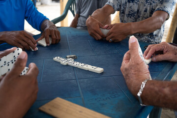 Un grupo de hombres están jugando dominó y están colocando las piezas de dominó en el centro de...