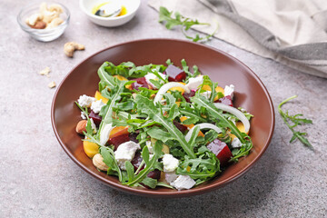 Tasty salad with arugula, cheese, peach, beetroot and nuts on grey table, closeup
